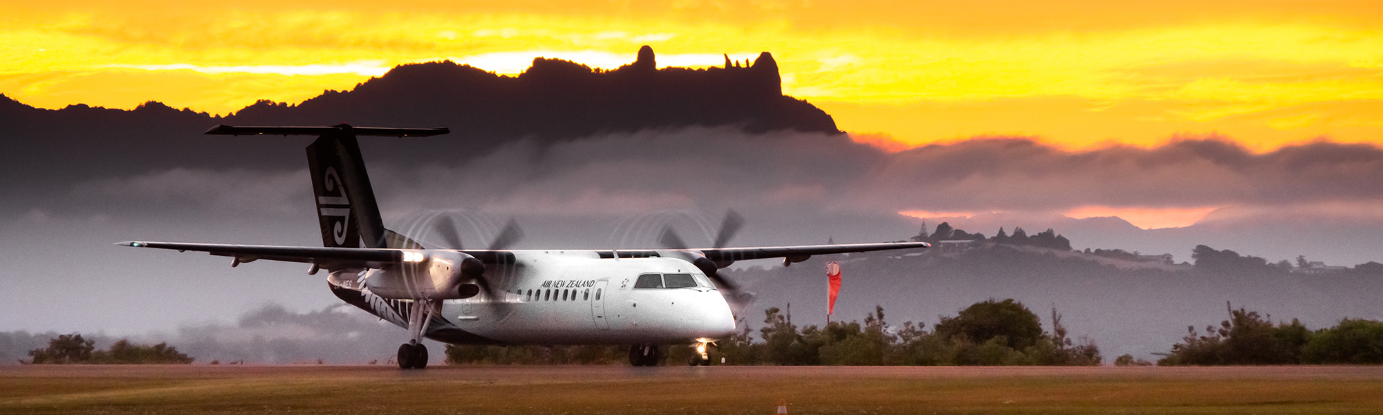 Plane on the tarmac at the Whangārei airport with Mount Manaia and the sun in the background. 