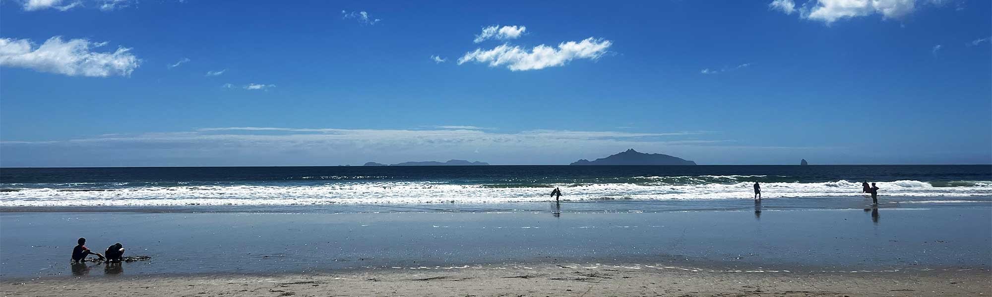 Children play at Waipu Cove beach on a beautiful sunny day