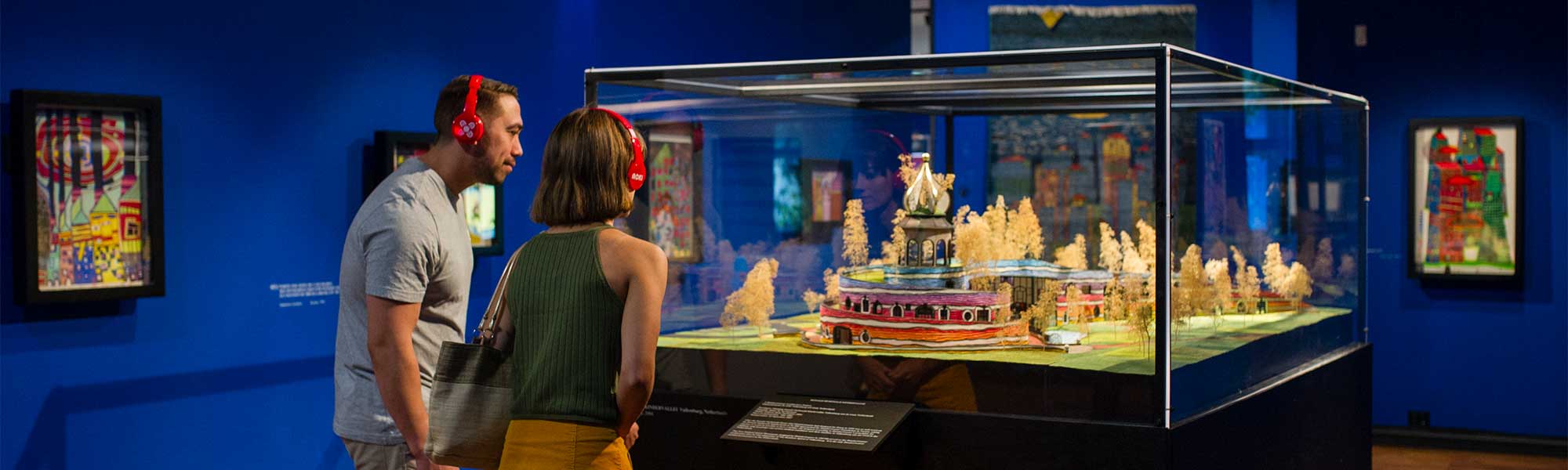 Couple looking at models created by Hundertwasser, while listening to an audio tour