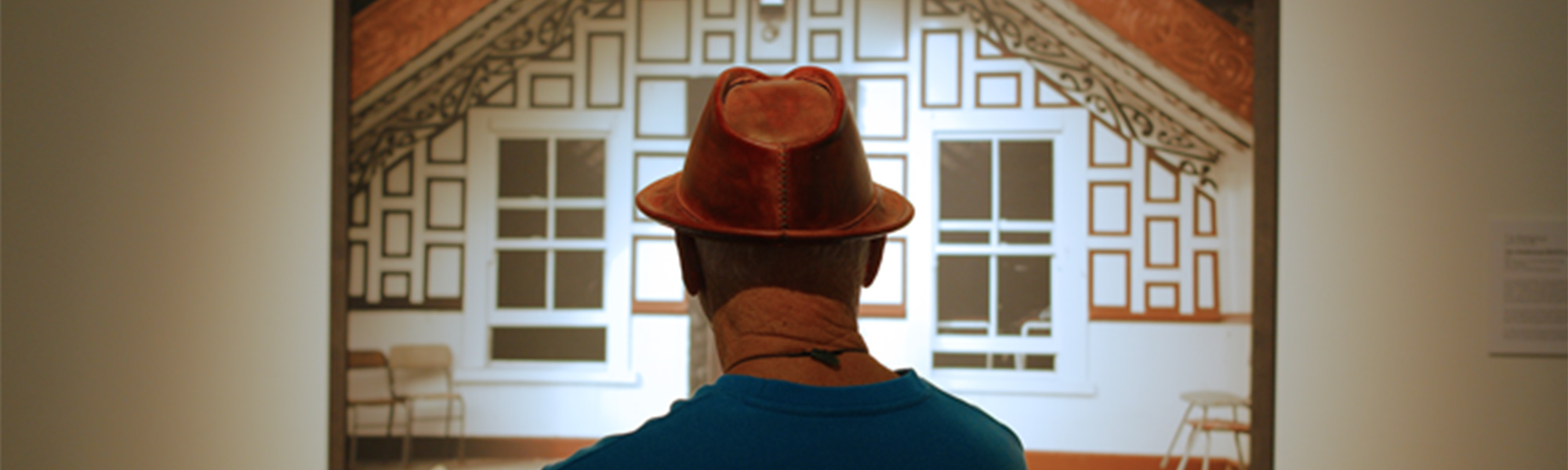 A man looks at an art piece of a whare at the Wairau Maori Art Gallery