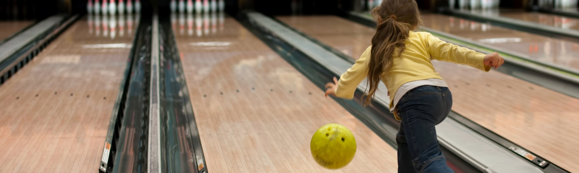 Young girl bowling a yellow ball