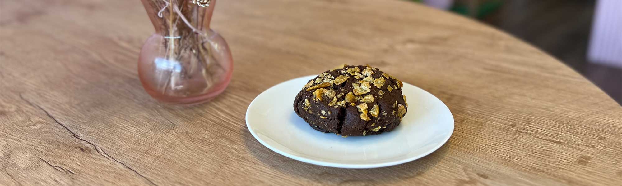 A cornflake cookie from Cuppacakes on a table with flowers